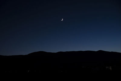 Silhouette mountains against clear sky at night