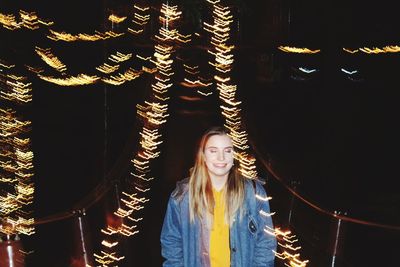 Smiling young woman standing against light painting