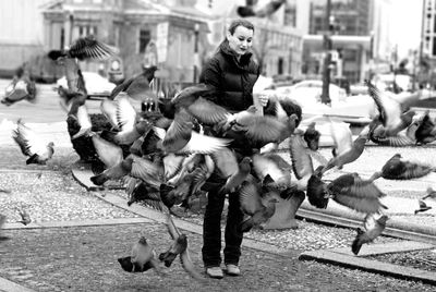 Full length of woman feeding pigeons in city during winter