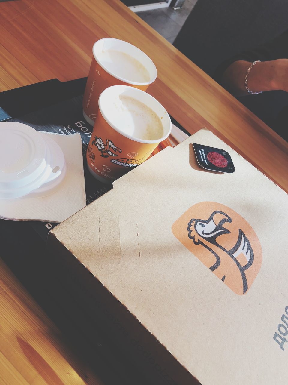 HIGH ANGLE VIEW OF HAND HOLDING COFFEE ON TABLE