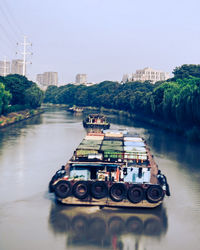 Cars on river in city against sky
