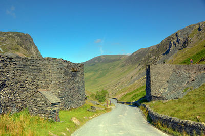 Road passing through mountain against blue sky