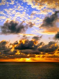 Scenic view of sea against dramatic sky during sunset