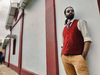 Young man wearing sunglasses standing against wall