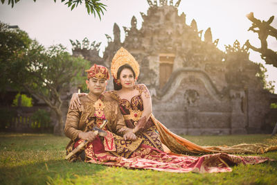 Portrait of smiling couple sitting against old ruins