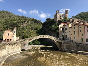 Arch bridge over river amidst buildings against sky