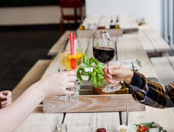 Cropped hands of people toasting drinks on table