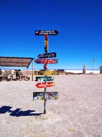 Information signs at beach against clear sky during sunny day