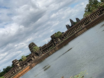 Building by river against cloudy sky