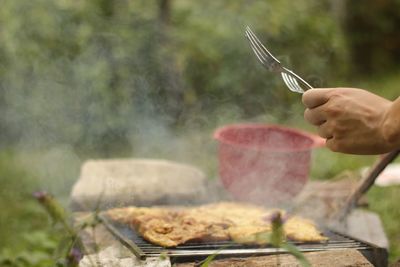 Midsection of person preparing food on barbecue grill