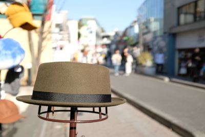 Close-up of hat on street against buildings in city