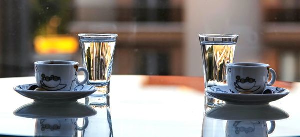 Coffee cups and water glasses on table