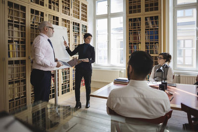 Male and female professionals giving presentation to coworkers in board room