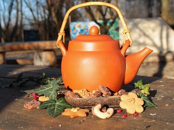 Still life with orange ceramic tea pot, sweets and leaves