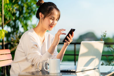 Young woman using mobile phone while sitting on table