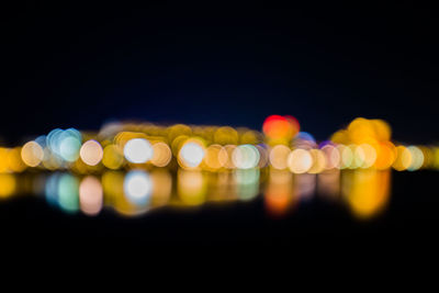 Defocused image of illuminated lights against black background