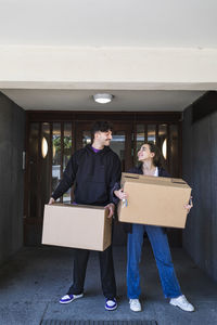 Smiling couple carrying cardboard boxes