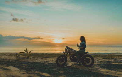 Man riding bicycle at beach during sunset