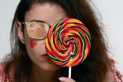 Young woman holding colorful lollipop against white background