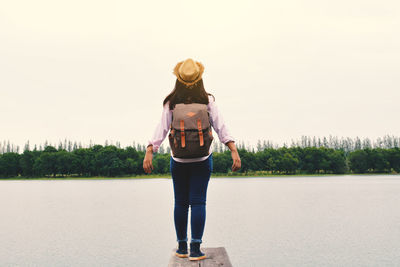 Full length of woman standing on pier by lake