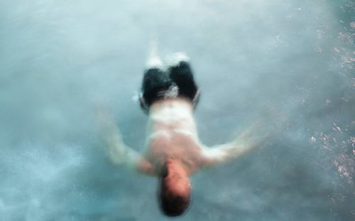 Rear view of shirtless woman swimming in sea