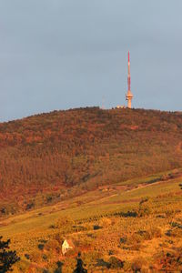 Communications tower on hill against sky