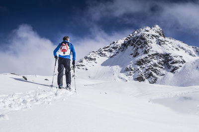 Rear view of person on snowcapped mountain against sky