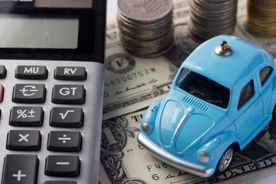 Close-up of toy car by calculator and currency against white background