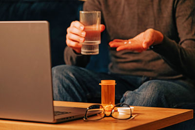 Midsection of man using laptop at table