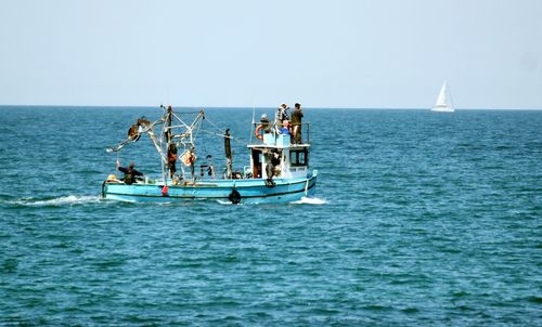 People in boat on sea against clear sky