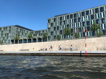 People by building against clear blue sky