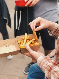 Midsection of person holding french fries