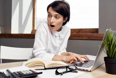 Young woman using mobile phone while sitting on table