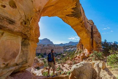 Man standing on rock formation against sky