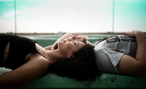 Portrait of woman lying on floor against sky