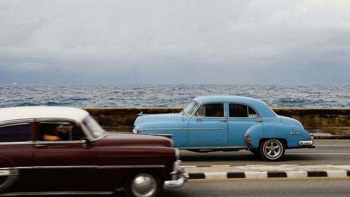 Vintage car on sea shore against sky