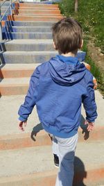 Rear view of boy walking on staircase