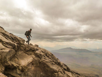 Man standing on mountain against cloudy sky