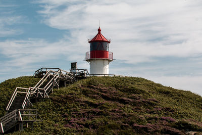 Lighthouse by sea against sky