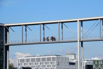 Low angle view of elevated walkway and buildings in city against sky