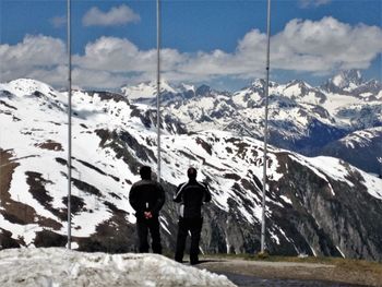 Rear view of two people walking on snow covered mountain