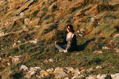 Side view of woman sitting on field