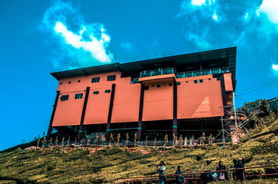 Low angle view of building on field against blue sky