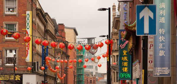 Multi colored lanterns hanging in city against sky