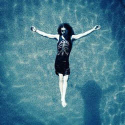 Full length of woman with arms raised in water