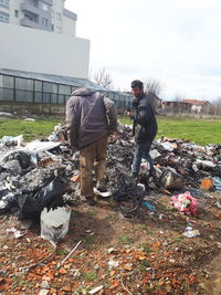 Man working with garbage in front of built structure