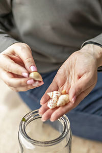 Women's hands hold seashells. puts the shells in a glass jar. beach treasures