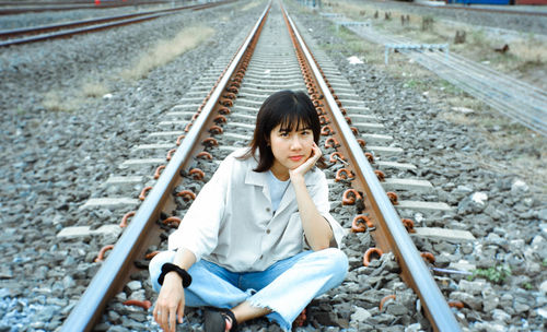 Portrait of woman sitting on railroad track