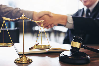 Midsection of lawyer shaking hands with man