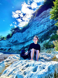 Portrait of teenage girl sitting on rock